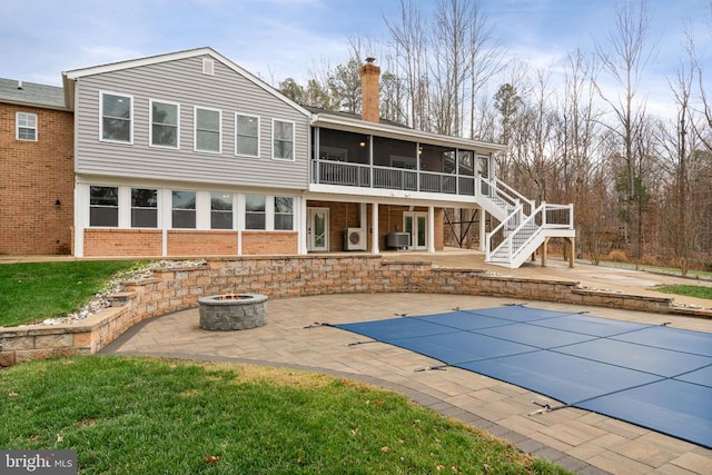 back of property featuring a sunroom, an outdoor fire pit, a covered pool, central AC unit, and a patio