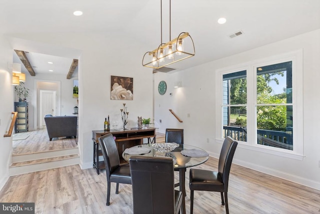 dining area featuring beamed ceiling and light wood-type flooring