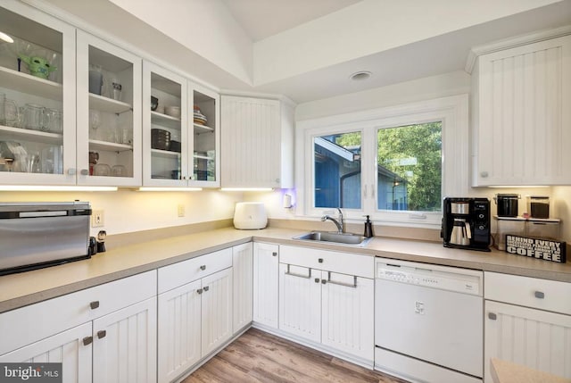 kitchen featuring white dishwasher, white cabinets, sink, and light hardwood / wood-style flooring