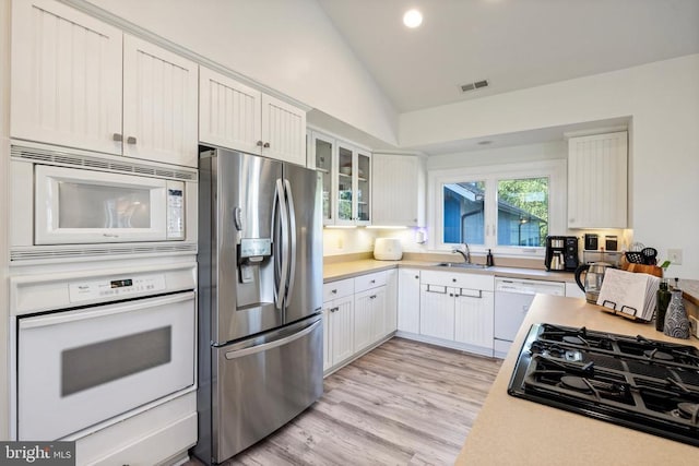 kitchen with white cabinetry, lofted ceiling, light hardwood / wood-style floors, and white appliances