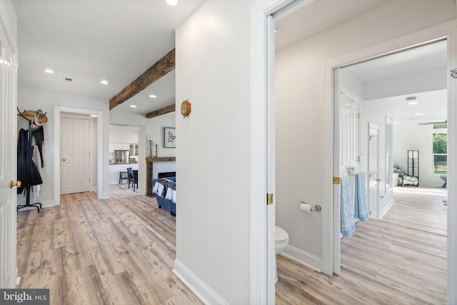 corridor with light hardwood / wood-style flooring and beamed ceiling