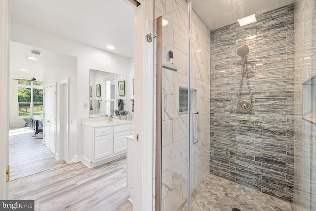 bathroom with hardwood / wood-style floors, vanity, and a shower with door