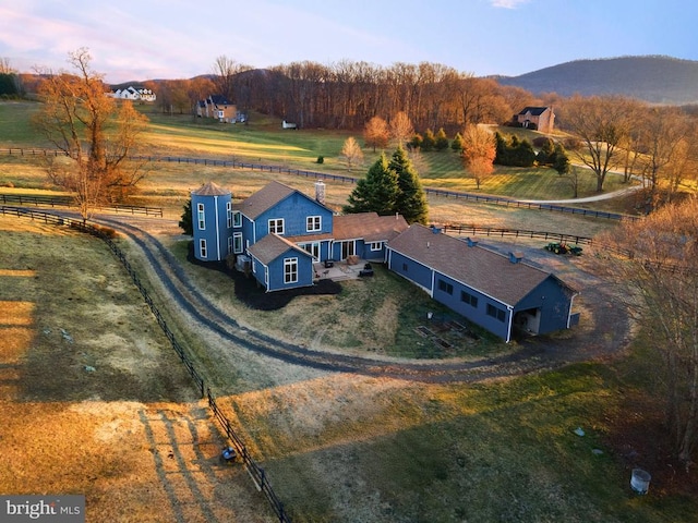 aerial view at dusk featuring a mountain view and a rural view