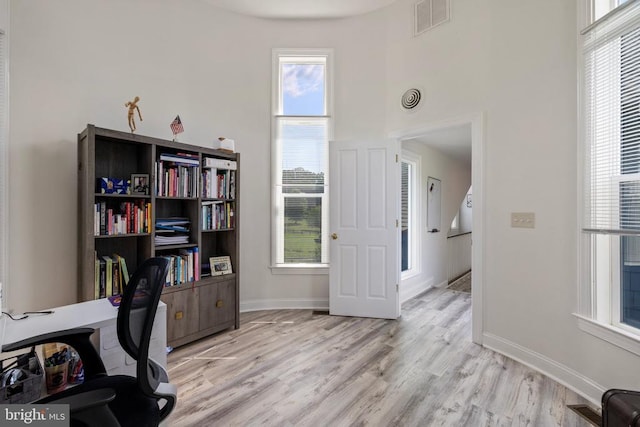 office space featuring a towering ceiling and light wood-type flooring