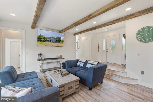 living room featuring beamed ceiling and light hardwood / wood-style floors