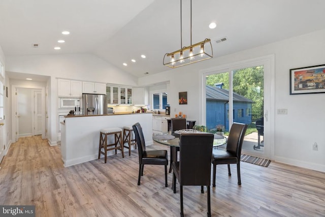 dining area with light wood-type flooring and lofted ceiling