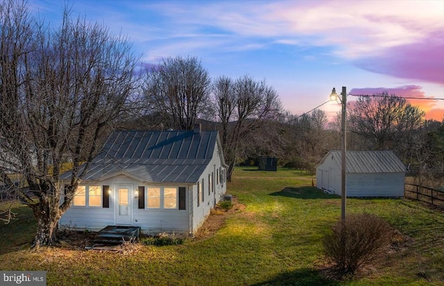 property exterior at dusk featuring a yard and an outbuilding