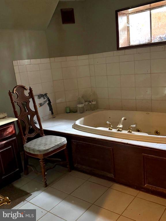 bathroom featuring tile patterned flooring, vaulted ceiling, tile walls, and tiled tub