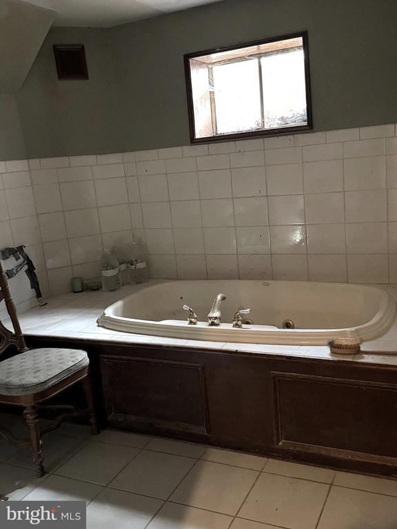 bathroom featuring tile patterned floors, a bathtub, and tile walls