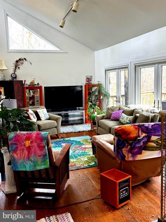 living room with french doors, hardwood / wood-style flooring, track lighting, and lofted ceiling