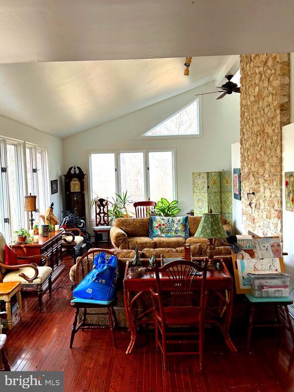 dining area with ceiling fan, lofted ceiling with beams, and wood-type flooring