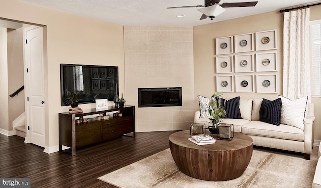 living room with dark hardwood / wood-style flooring, a fireplace, and ceiling fan