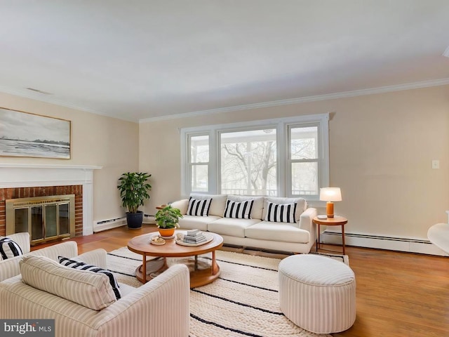 living room featuring baseboard heating, crown molding, a fireplace, and light hardwood / wood-style flooring