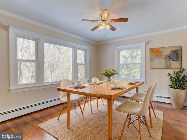 dining space featuring hardwood / wood-style floors, baseboard heating, ornamental molding, and ceiling fan