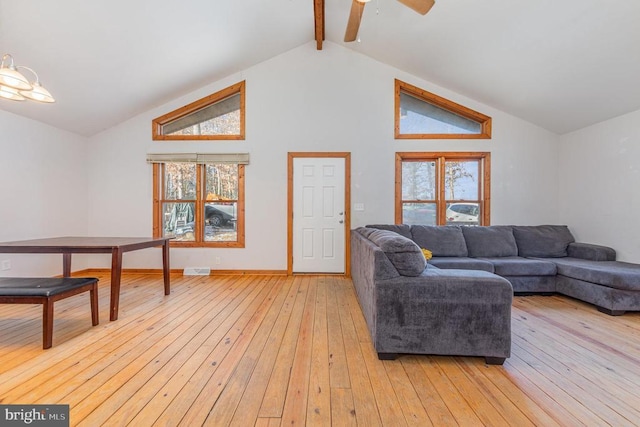 living room featuring ceiling fan, a healthy amount of sunlight, light hardwood / wood-style flooring, and vaulted ceiling with beams