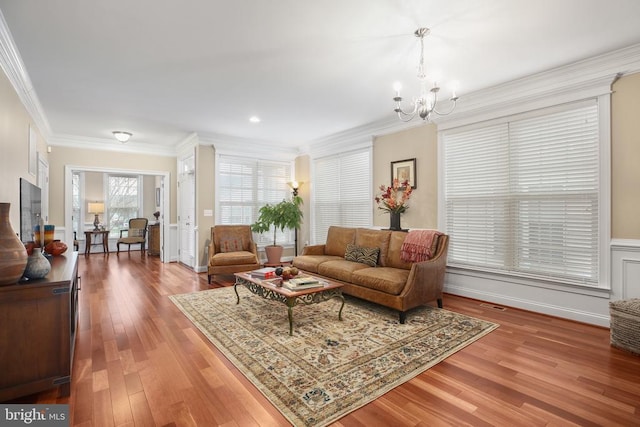 living room with crown molding, an inviting chandelier, and hardwood / wood-style flooring