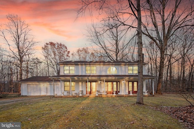 view of front of property with a lawn, a porch, and a garage