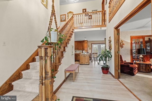 stairway featuring hardwood / wood-style flooring, a high ceiling, and french doors