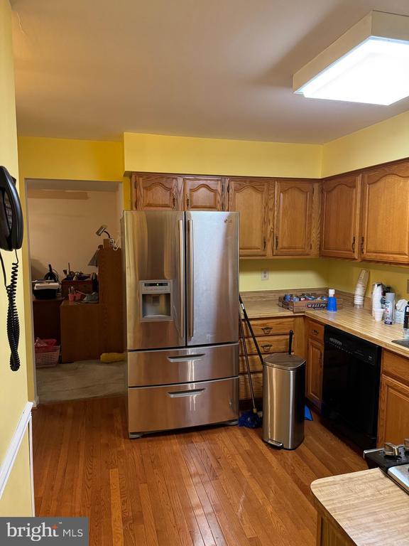 kitchen with hardwood / wood-style flooring, black dishwasher, and stainless steel refrigerator with ice dispenser