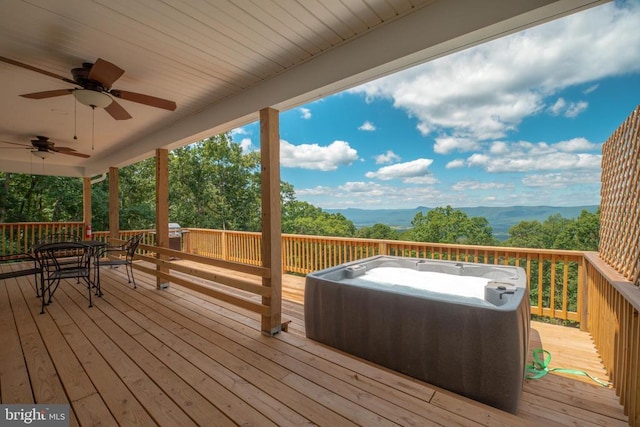 wooden deck featuring a mountain view, a hot tub, and ceiling fan