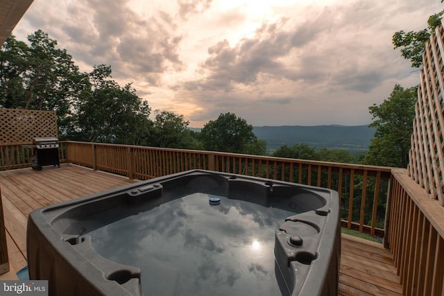 deck at dusk featuring a mountain view, area for grilling, and a hot tub