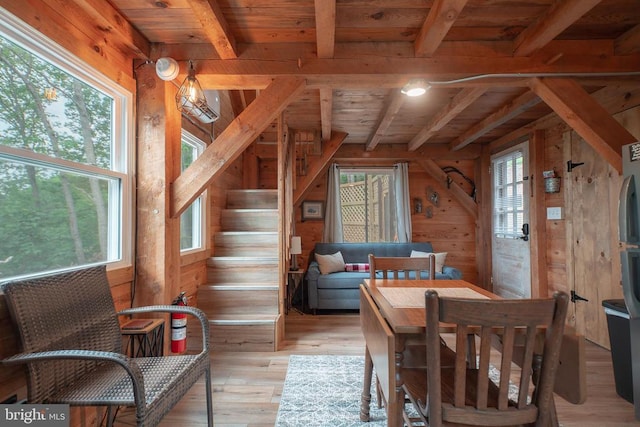 dining room featuring a wealth of natural light, wood walls, light hardwood / wood-style flooring, and wooden ceiling