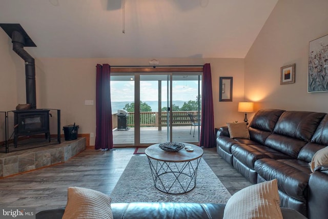 living room featuring a wood stove, vaulted ceiling, and hardwood / wood-style flooring