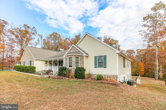 view of front facade featuring central AC, covered porch, and a front yard