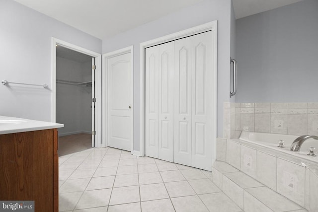 bathroom with tile patterned flooring, vanity, and tiled bath