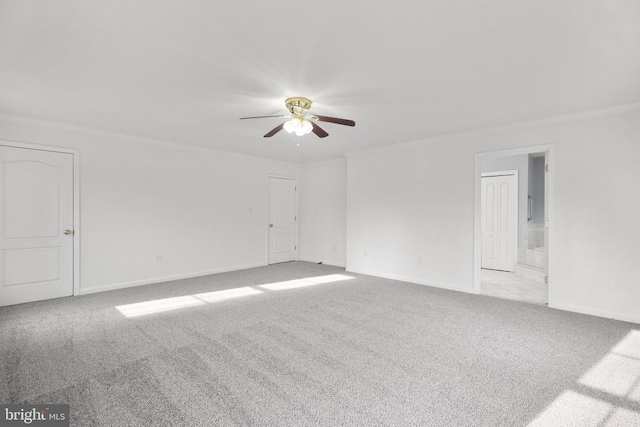 spare room with ceiling fan, crown molding, and light carpet