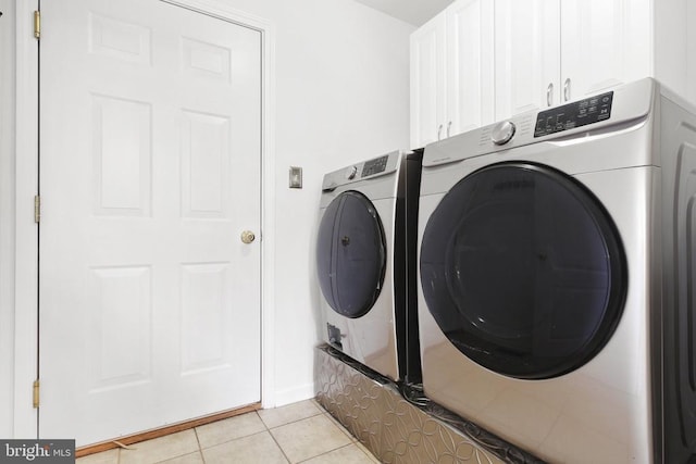 washroom with cabinets, independent washer and dryer, and light tile patterned floors