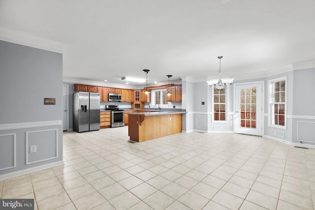 kitchen featuring kitchen peninsula, a breakfast bar, stainless steel appliances, crown molding, and decorative light fixtures