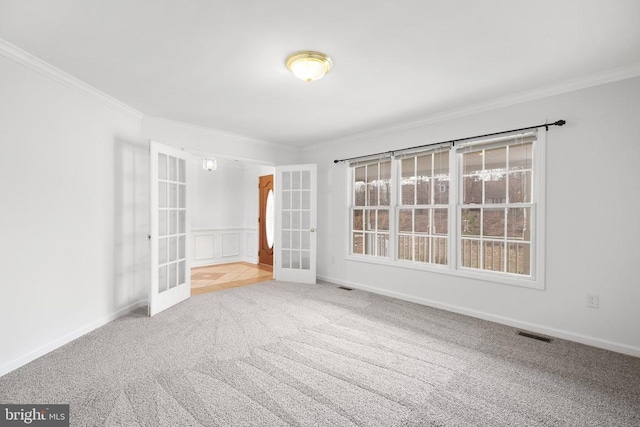 empty room with french doors, light colored carpet, and ornamental molding