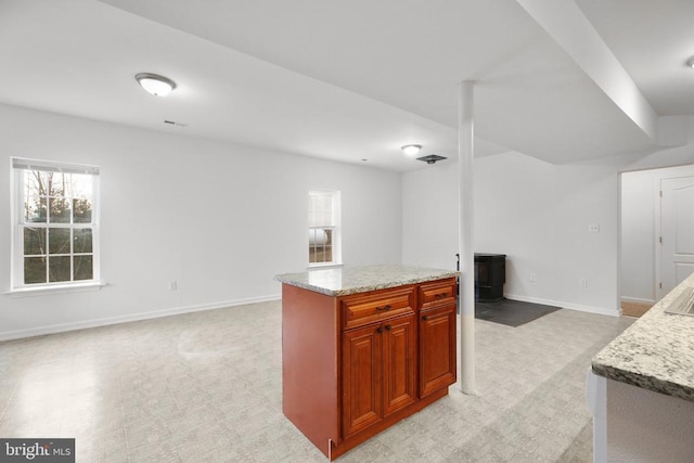 kitchen featuring light carpet, light stone counters, and a kitchen island