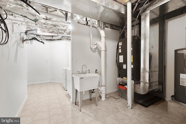 basement featuring washer and clothes dryer, electric water heater, and sink