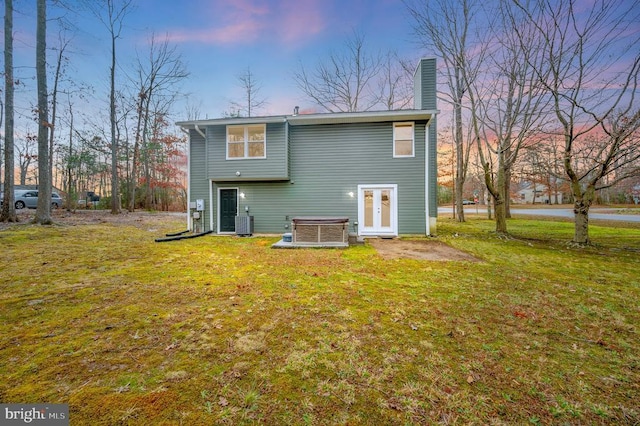 back house at dusk with a yard and central AC unit