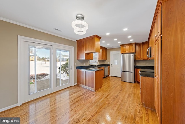 kitchen featuring light hardwood / wood-style floors, crown molding, appliances with stainless steel finishes, and an inviting chandelier