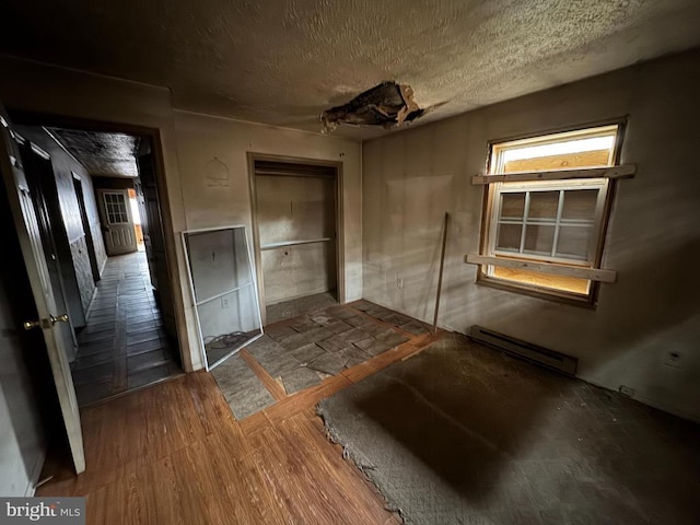 misc room featuring a textured ceiling and a baseboard heating unit