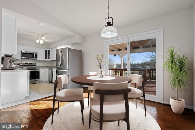 dining room with ceiling fan, light hardwood / wood-style flooring, and vaulted ceiling