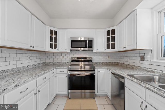 kitchen featuring appliances with stainless steel finishes, light tile patterned floors, and white cabinetry