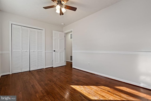 unfurnished bedroom featuring ceiling fan, a closet, and dark wood-type flooring