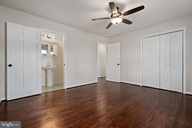 unfurnished bedroom featuring ceiling fan, a closet, dark wood-type flooring, and ensuite bath