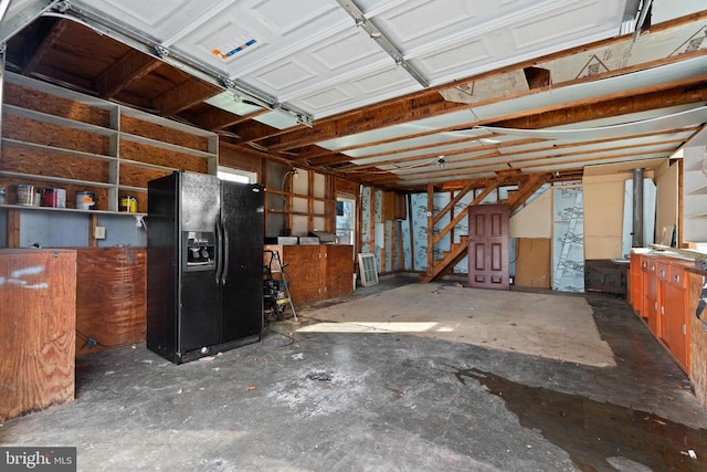 garage featuring black refrigerator with ice dispenser