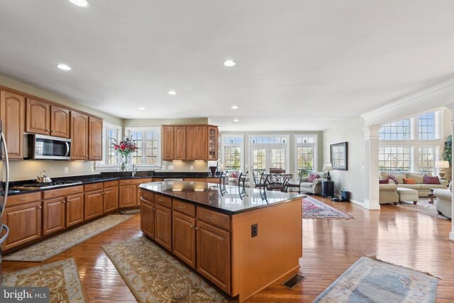 kitchen with dark stone counters, sink, light hardwood / wood-style floors, a kitchen island, and stainless steel appliances