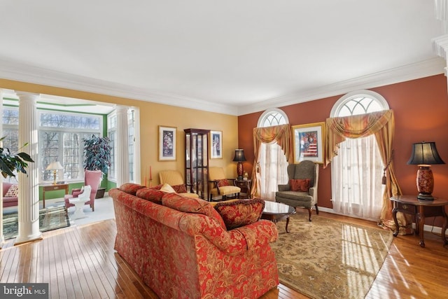 living room featuring light wood-type flooring, crown molding, and decorative columns