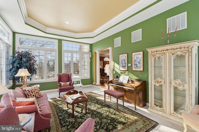 sitting room with decorative columns, a raised ceiling, and ornamental molding