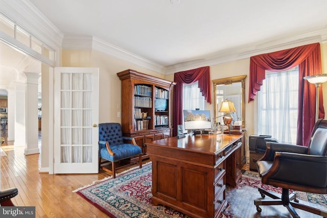 home office featuring ornate columns, ornamental molding, a healthy amount of sunlight, and light wood-type flooring