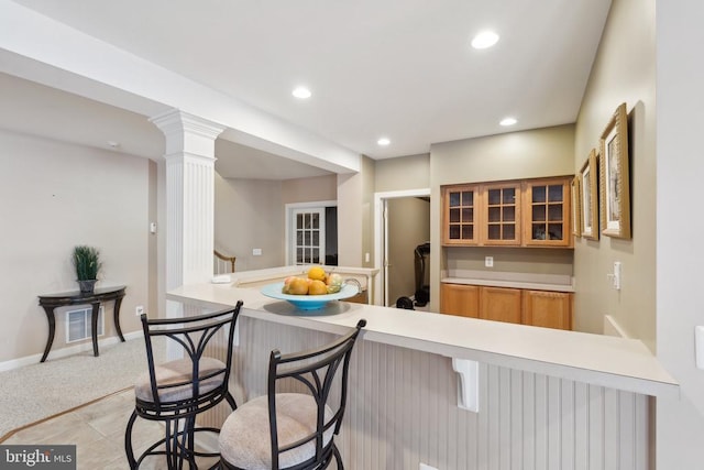 kitchen featuring kitchen peninsula, light carpet, and a breakfast bar area