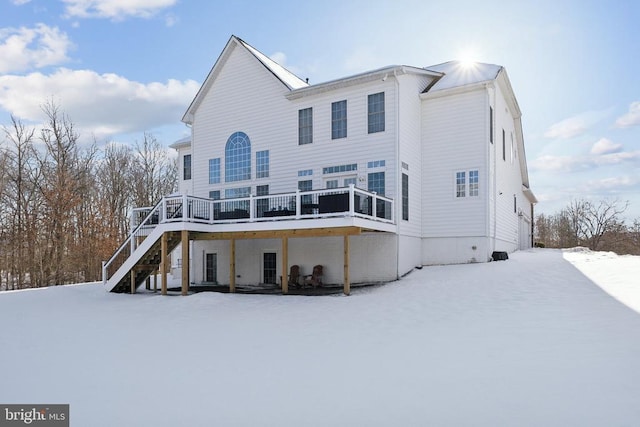 snow covered house with a wooden deck