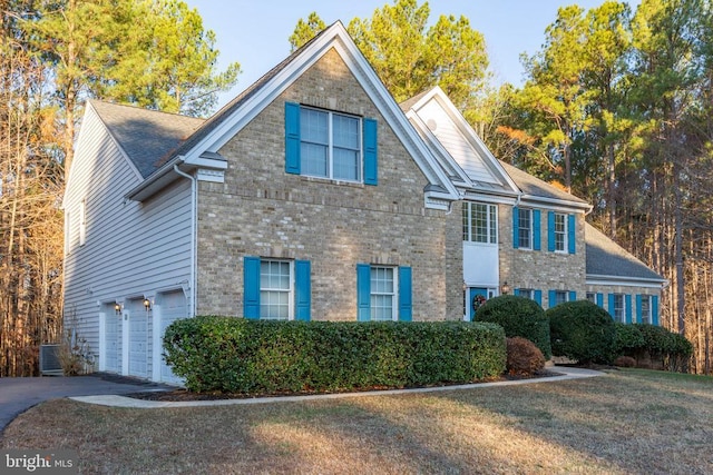 view of front of home featuring a front lawn, central AC unit, and a garage